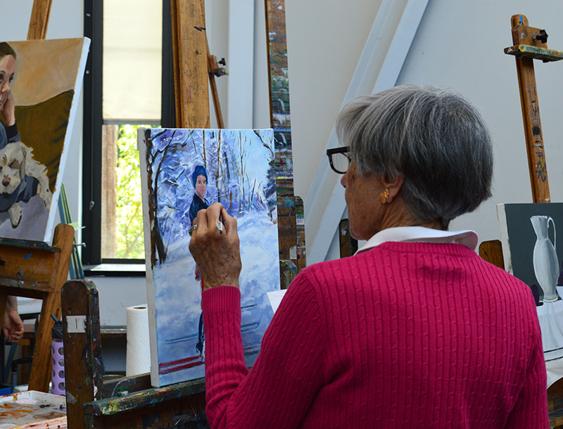 A woman artist painting in the studio.