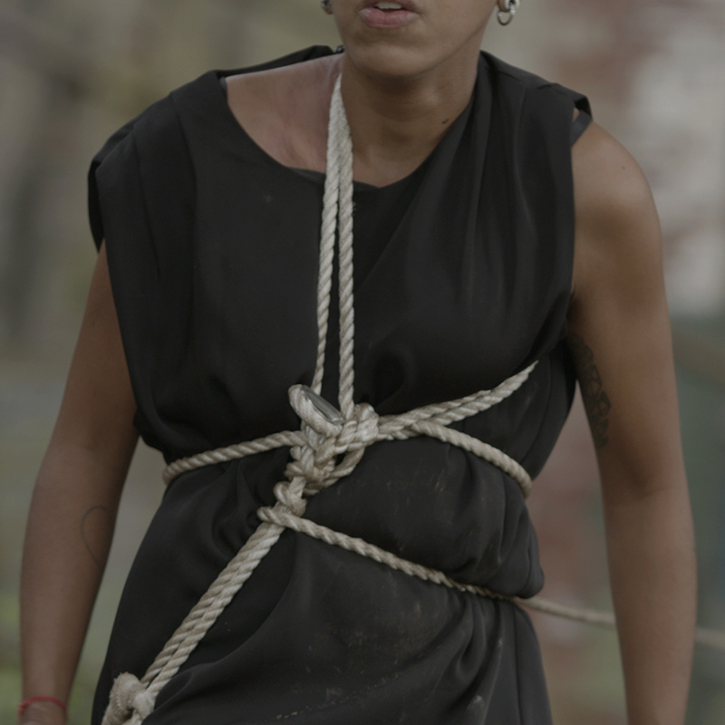 Anna Parisi, Caught in the Act, 2020, video still. Courtesy of the artist. Depicts a person in black, with white ropes tied around their abdomen.