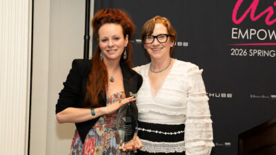 Two women stand together holding a glass award trophy in front of the 'art EMPOWERS! 2026 Spring Gala' backdrop. The award is from the Visual Arts Center of New Jersey. Sponsors Chubb and Brown & Brown Risk are visible in the background.